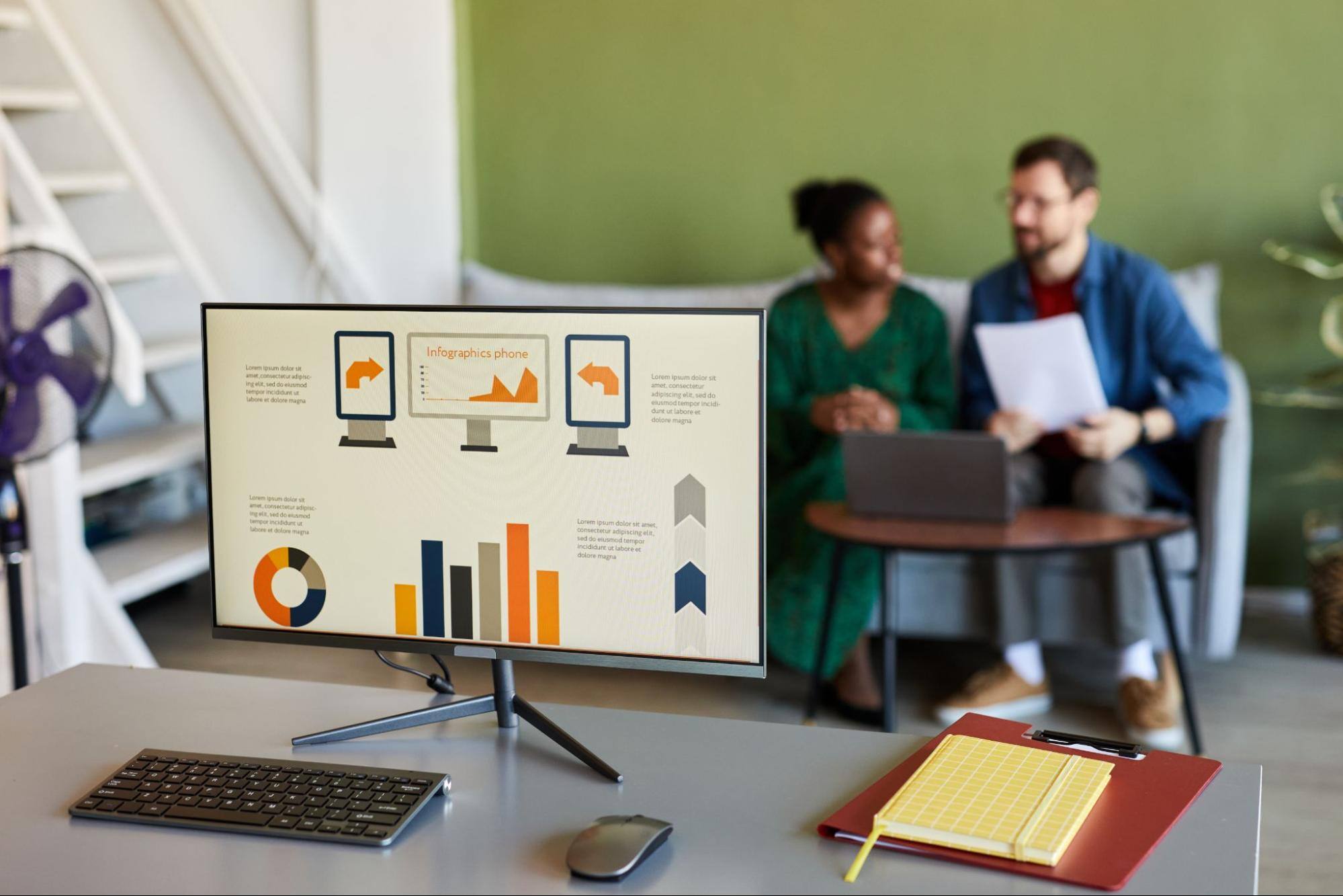 A computer screen shows a data report, while in the background are the employees.