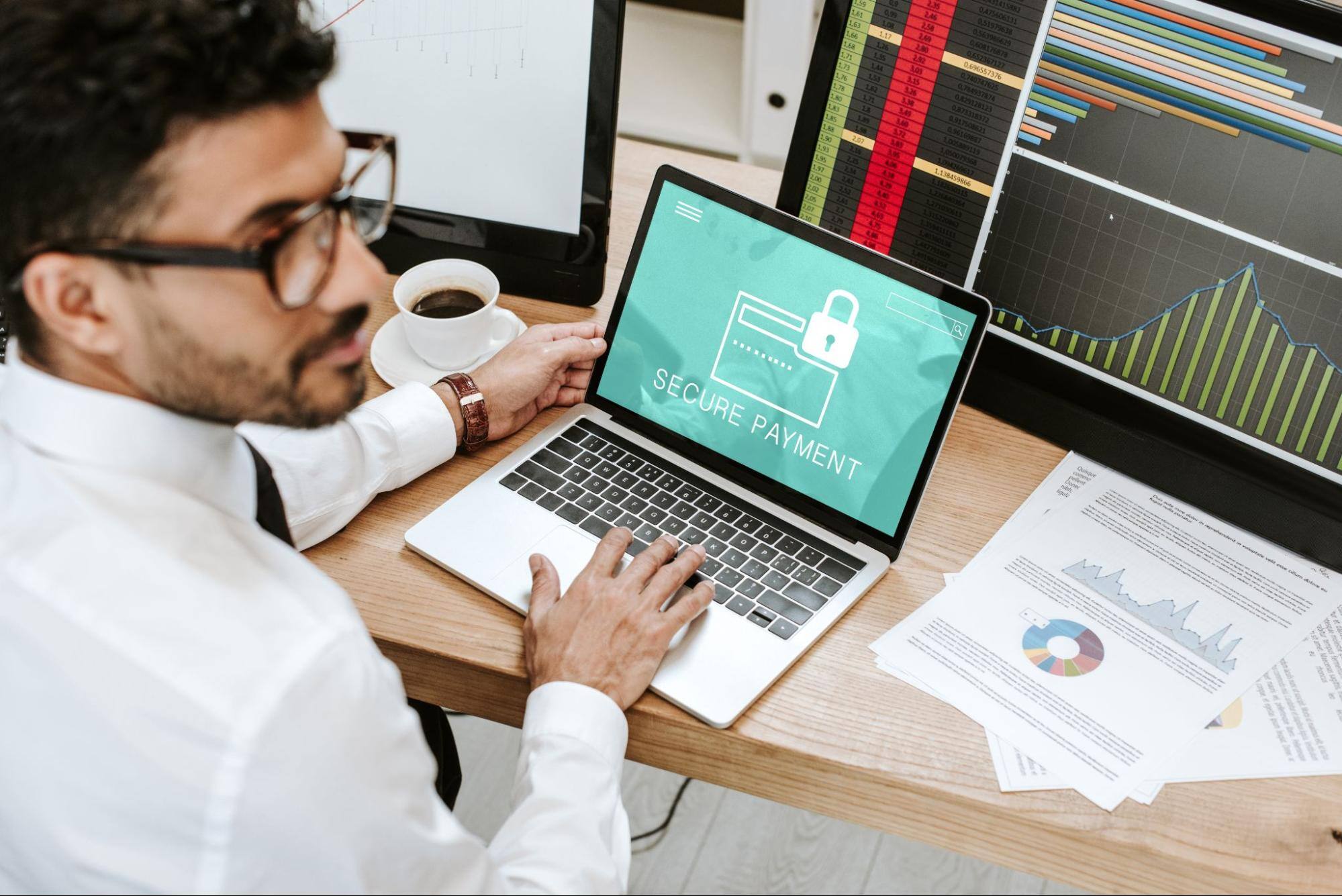 A man wearing glasses and a button-up white shirt with a laptop in front of him  saying, “secure payment.”