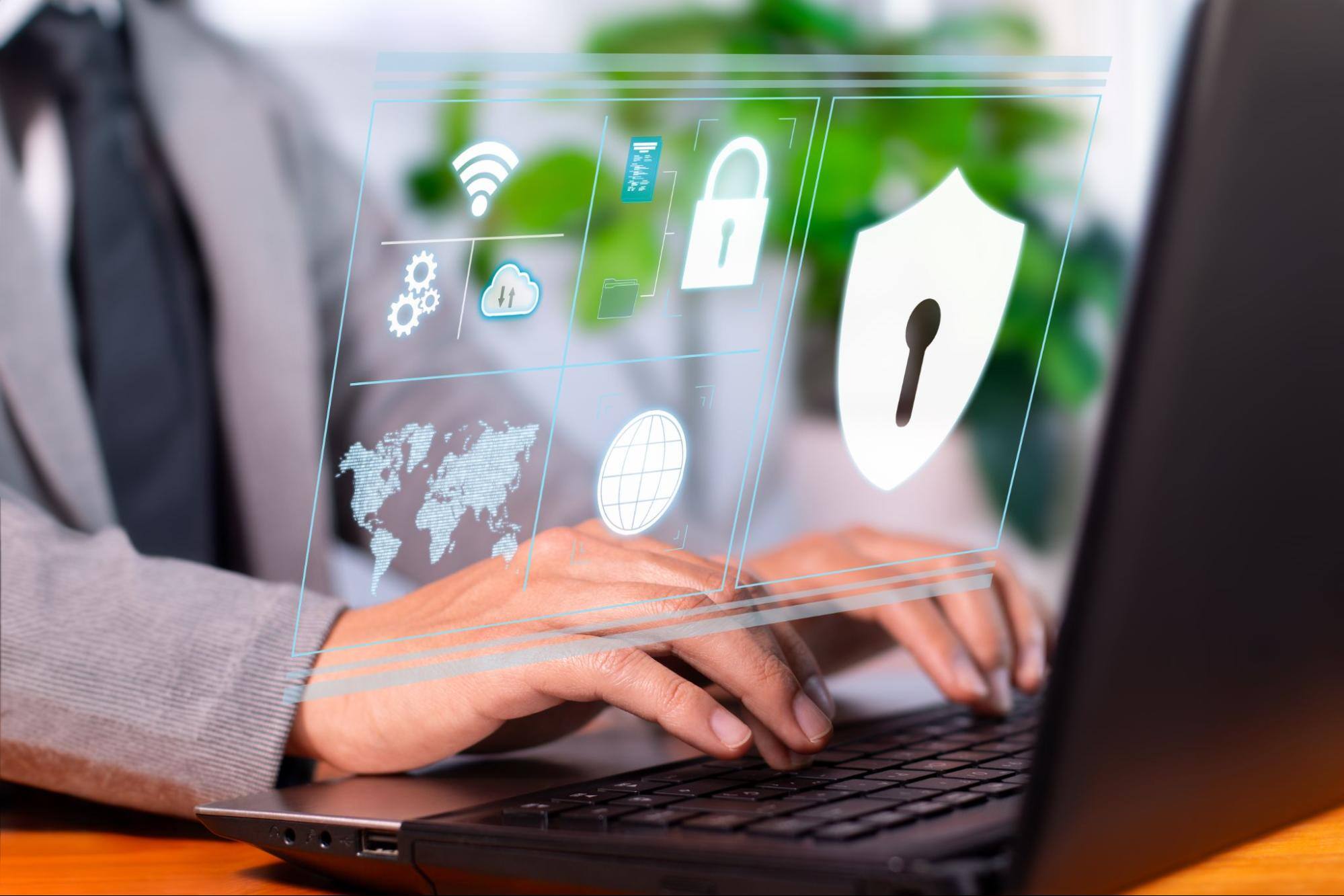  Man typing on a computer with security icons above the keyboard. 